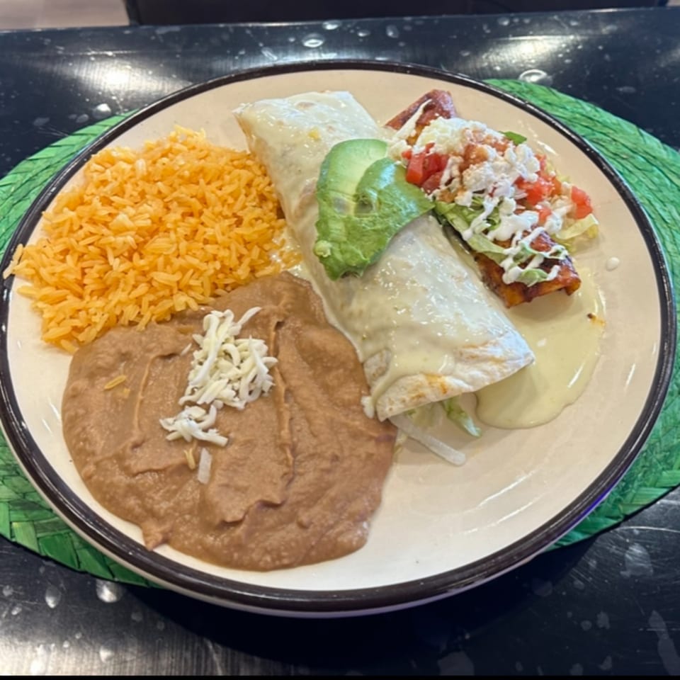 A Mexican combination plate with a burrito, taco, rice, and refried beans on a white plate.