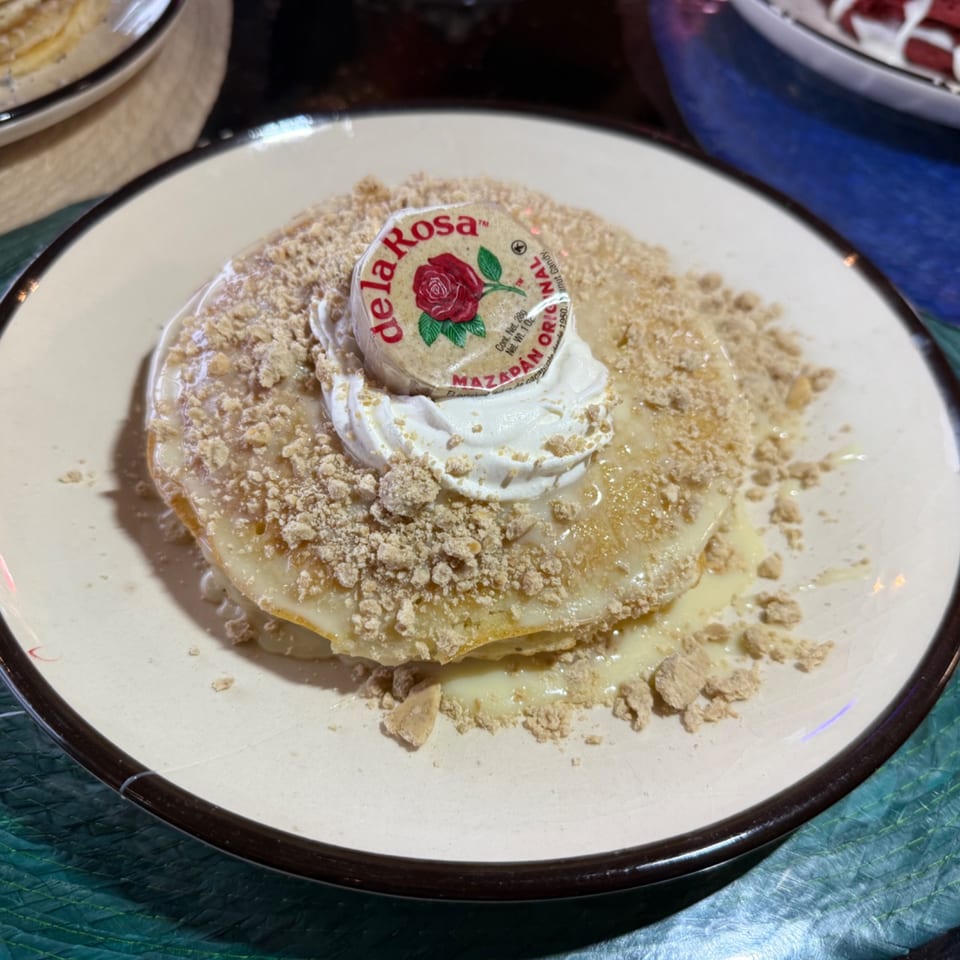 Pancakes topped with white sauce, crumbled mazapan, whipped cream, and a De La Rosa mazapan candy.